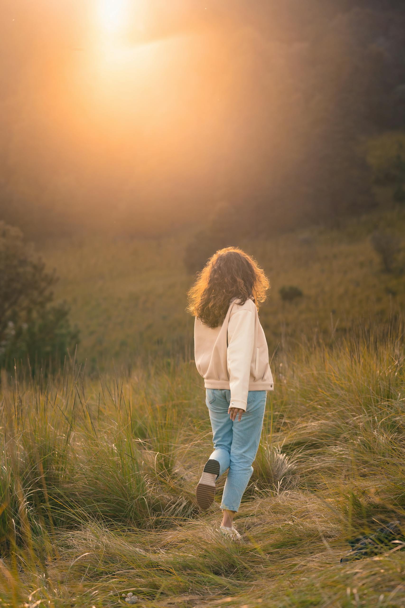 A girl walks through a sunlit meadow, capturing the essence of a tranquil autumn day.