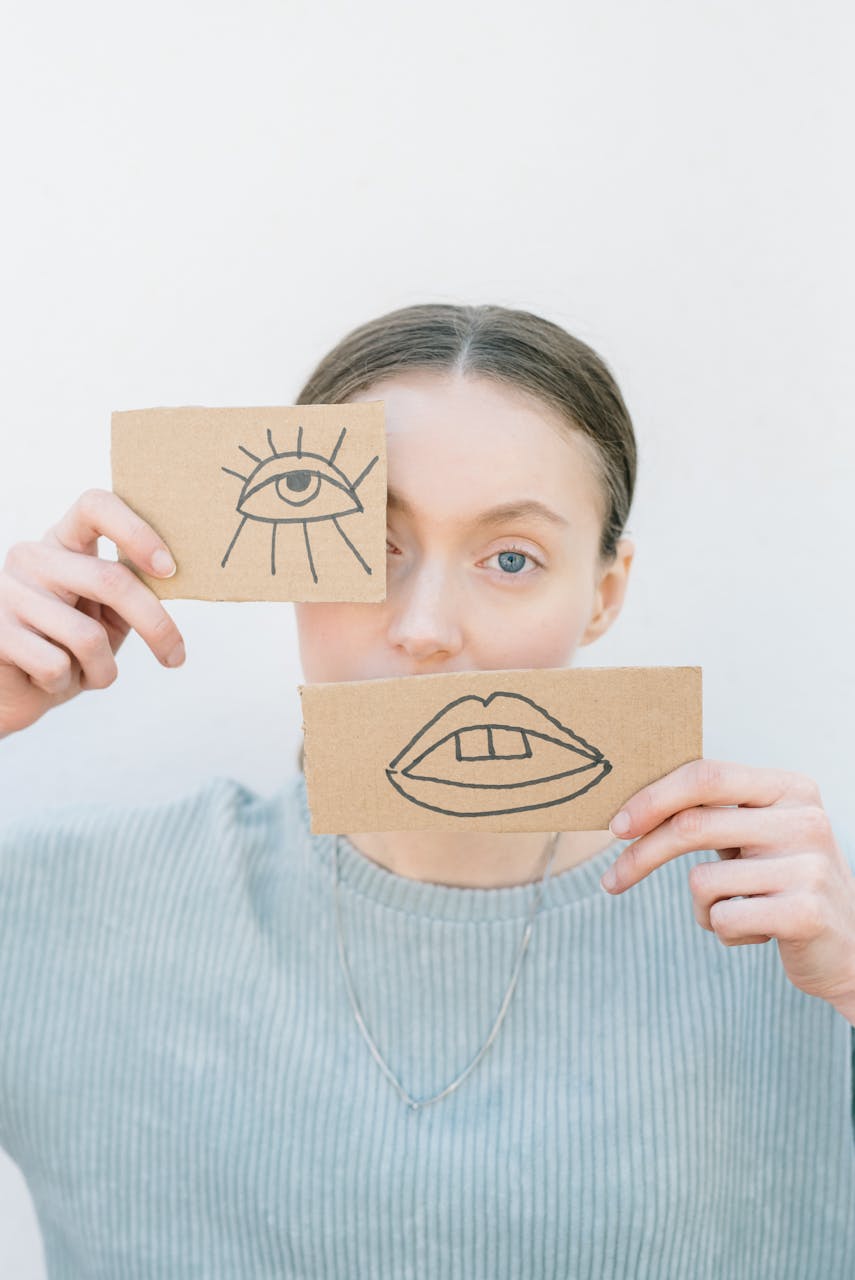 Woman with adult autism holding cardboard illustrations of eye and mouth.