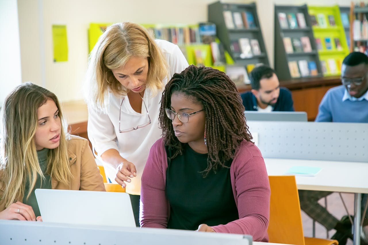 University students getting support from a teacher on a project in a library setting.
