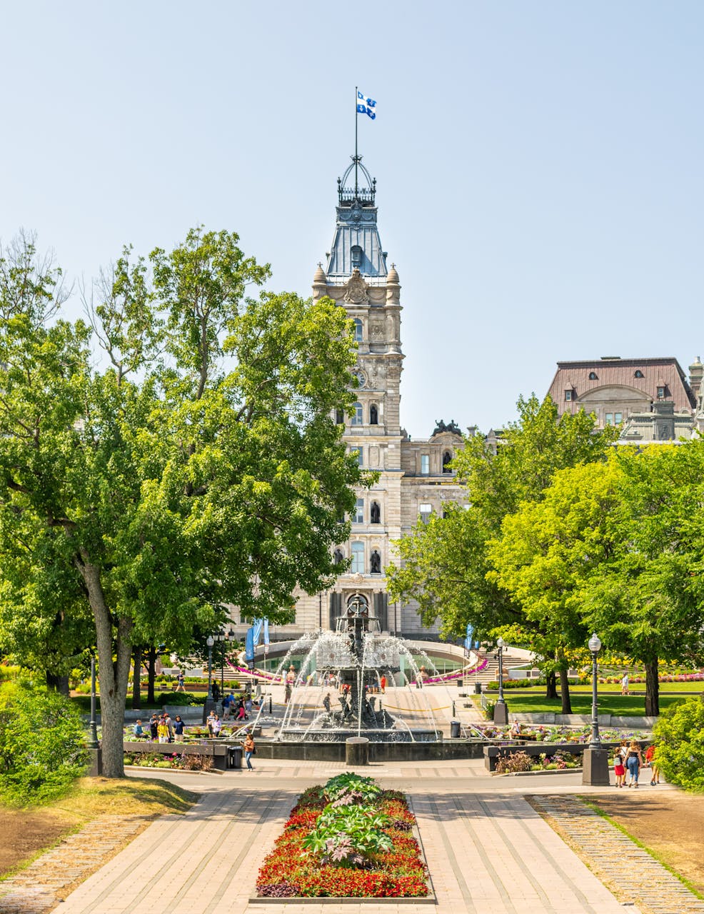 Une vue panoramique de l’édifice du Parlement de Québec et de la Fontaine de Tourny par une journée ensoleillée.