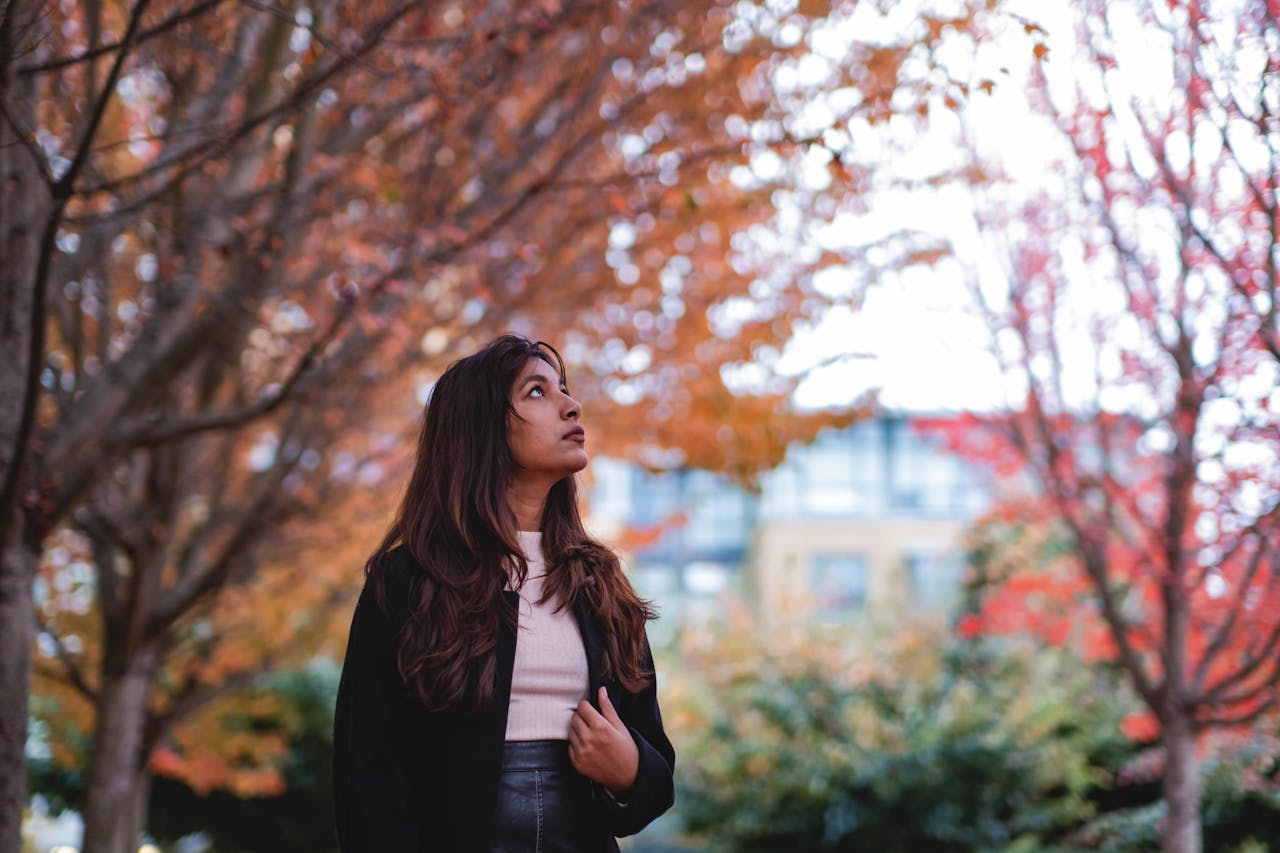 A woman enjoying the vibrant autumn colors under a canopy of trees in Vancouver, Canada.