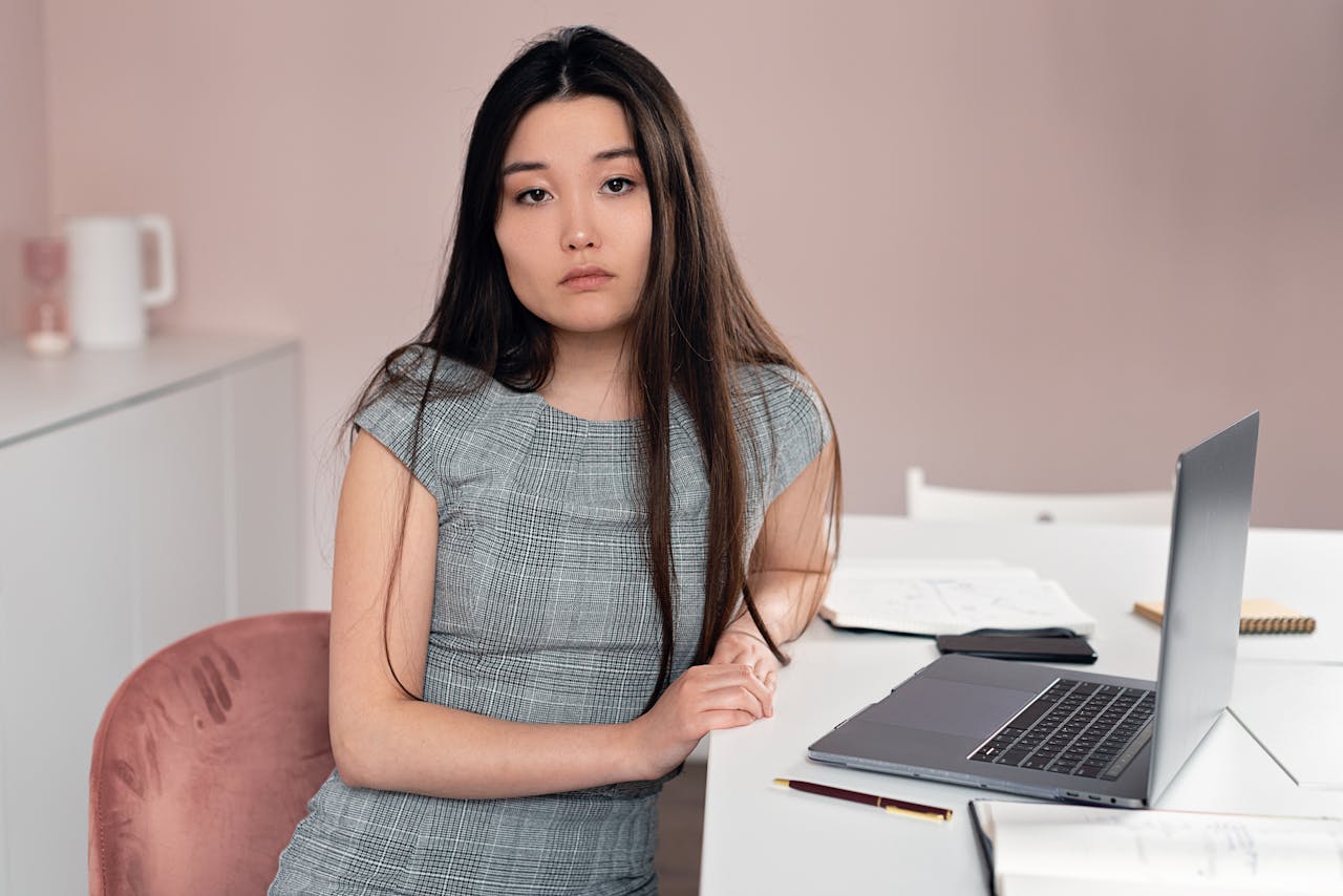 Asian woman sitting with laptop at office desk thinking about ADHD