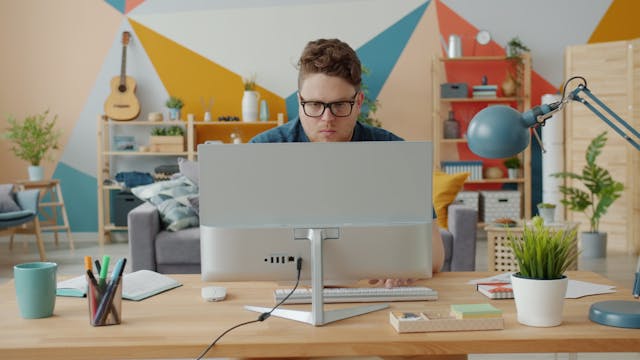 Man working intently at computer in a colorful home office setup.