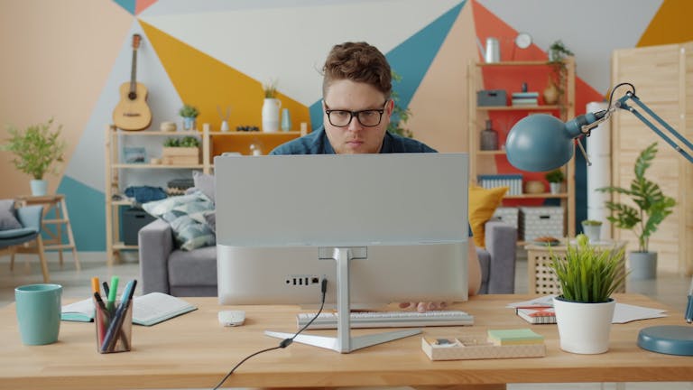 Man working intently at computer in a colorful home office setup.