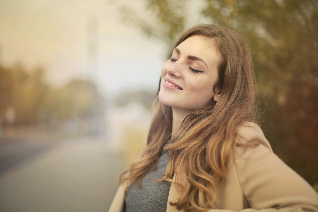 Portrait of a woman with closed eyes, enjoying the outdoors in autumn. Bright and serene.