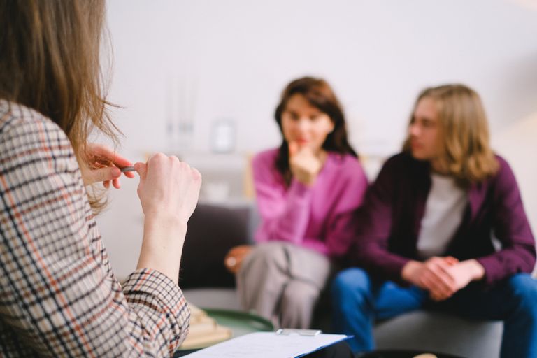A couple in therapy, guided by a professional therapist in a calm setting.