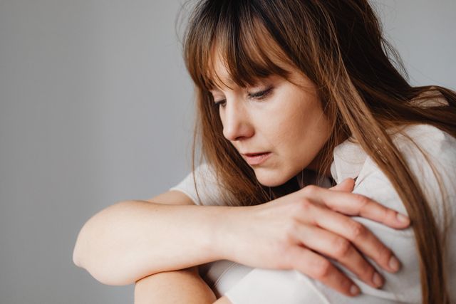 A woman sits with a serene expression, lost in deep thought.