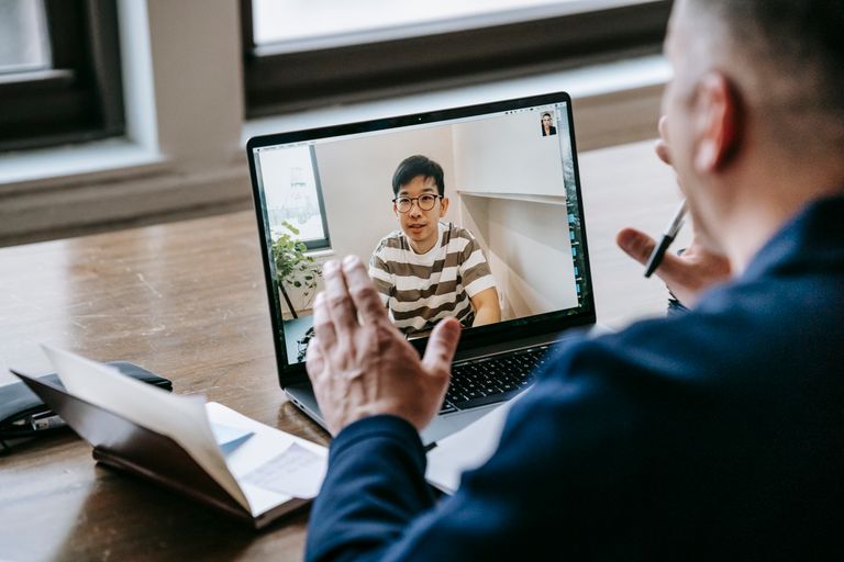 Two professionals engaged in an online video conference on a laptop in an indoor setting.