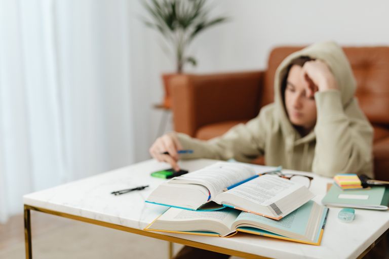 Teen focused on studying with books and notes on a home desk.
