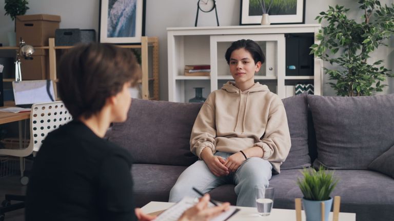 Teen undergoing therapy in modern office, showcasing supportive dialogue.